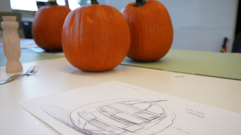 An industrial design student’s sketch is ready to apply to a waiting pumpkin.