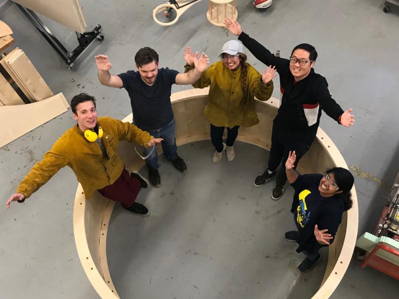 Students pose with a gigantic wheel they built.