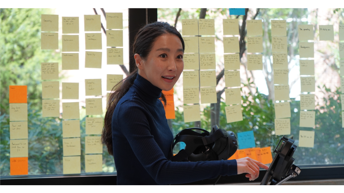 Professor Young-Mi Choi teaches a class in front of a window filled with sticky notes.