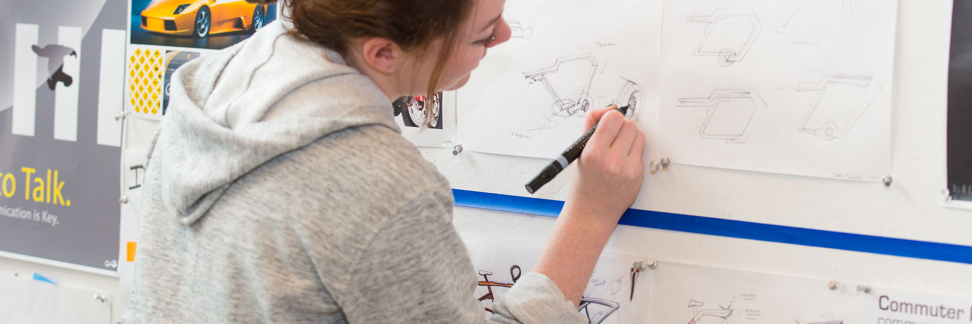 A student sketches on classwork that's pinned to a wall.